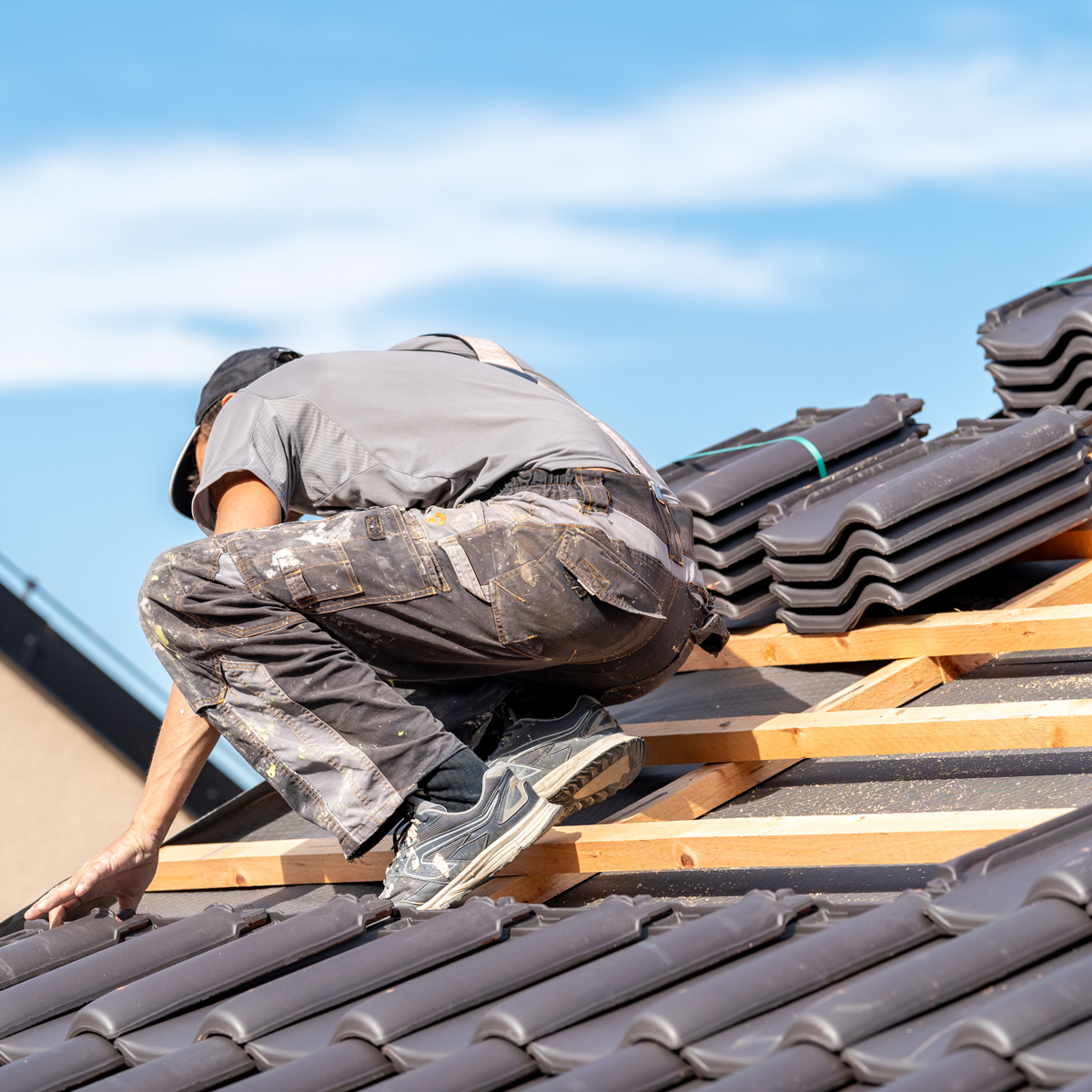 Roofer laying new roof tiles Roofer laying new roof tiles